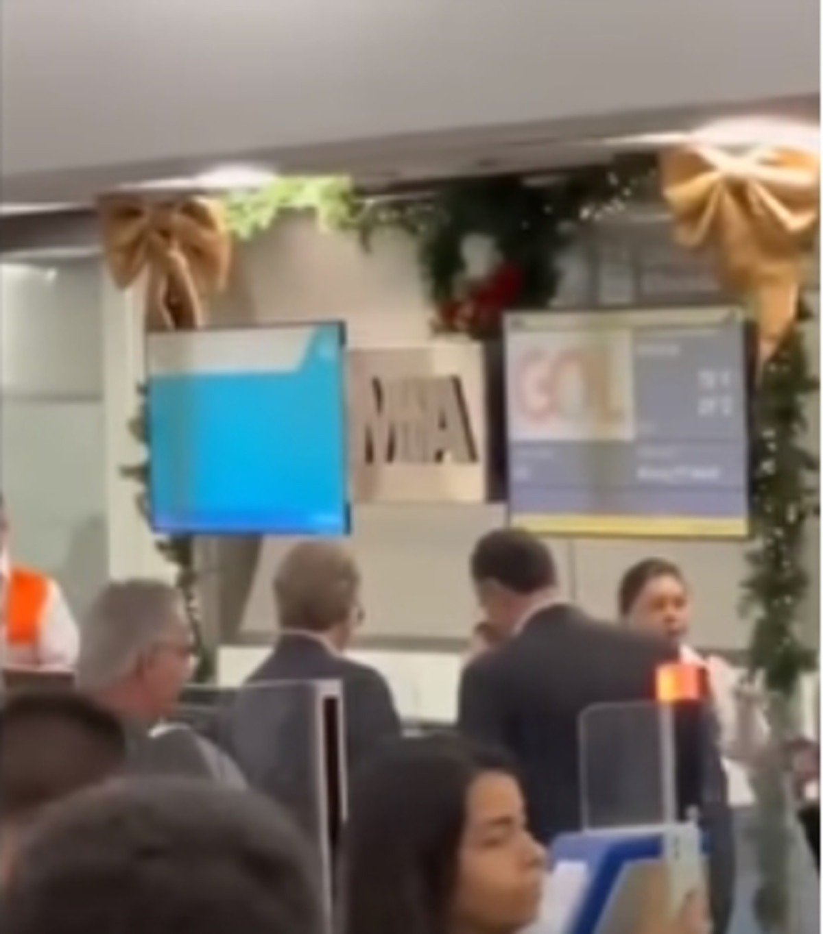 É possível confirmar que se trata do aeroporto de Miami, ao observar o logotipo ao fundo dos funcionários (MIA)