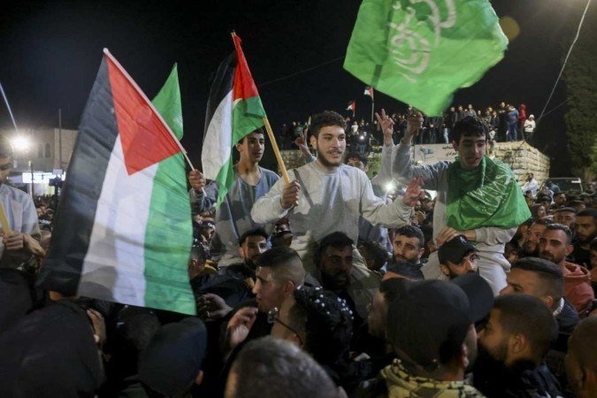 Prisioneiros palestinos que foram libertados das instalações militares israelenses de Ofer agitam bandeiras enquanto desfilam em Baytunia, na Cisjordânia -  (crédito: AHMAD GHARABLI/AFP)