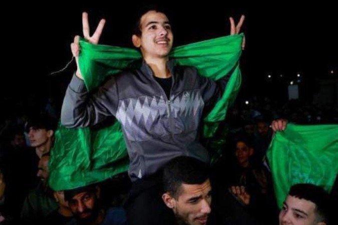 Um dos palestinos libertados é carregado nos ombros de um homem, envolto em uma bandeira -  (crédito: Reuters)