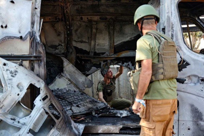 Membros das forças de segurança israelenses verificam um veículo destruído após ter sido atingido por um foguete disparado da Faixa de Gaza, no kibutz Mefalsim, perto da fronteira com o enclave palestino - (crédito: JACK GUEZ / AFP) Membros das forças de segurança israelenses verificam um veículo destruído após ter sido atingido por um foguete disparado da Faixa de Gaza, no kibutz Mefalsim, perto da fronteira com o enclave palestino - (crédito: JACK GUEZ / AFP)