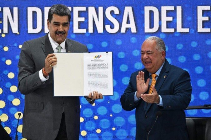 Nicolás Maduro (E) mostra a ata com o resultado da consulta popular de domingo, aplaudido pelo presidente do Conselho Nacional Eleitoral, Elvis Amoroso - (crédito: Federico Parra/AFP) Nicolás Maduro (E) mostra a ata com o resultado da consulta popular de domingo, aplaudido pelo presidente do Conselho Nacional Eleitoral, Elvis Amoroso - (crédito: Federico Parra/AFP)