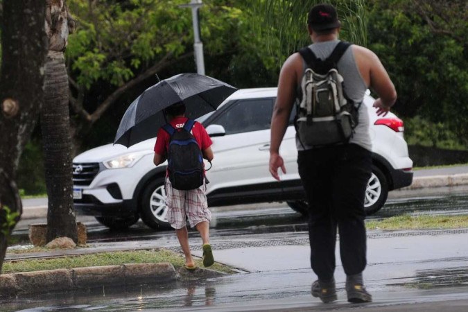 Homem se protege da chuva em Brasília. Previsão do tempo na semana do Natal é de muita água  -  (crédito: Minervino Júnior/CB/D.A.Press)