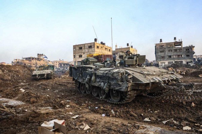 Esta foto tirada em 19 de dezembro de 2023 mostra tanques israelenses passando por edifícios danificados durante uma operação militar no norte da Faixa de Gaza - (crédito: GIL COHEN-MAGEN / AFP) Esta foto tirada em 19 de dezembro de 2023 mostra tanques israelenses passando por edifícios danificados durante uma operação militar no norte da Faixa de Gaza - (crédito: GIL COHEN-MAGEN / AFP)