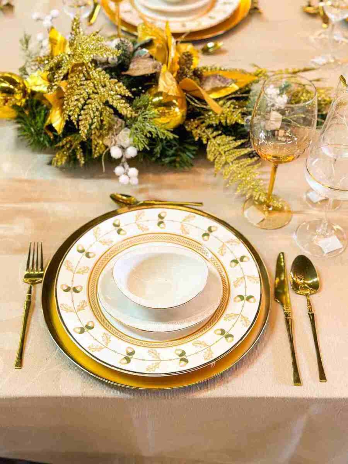 A louça com detalhes dourados conversa com os tons da toalha de mesa, o arranjo de centro e os talheres 