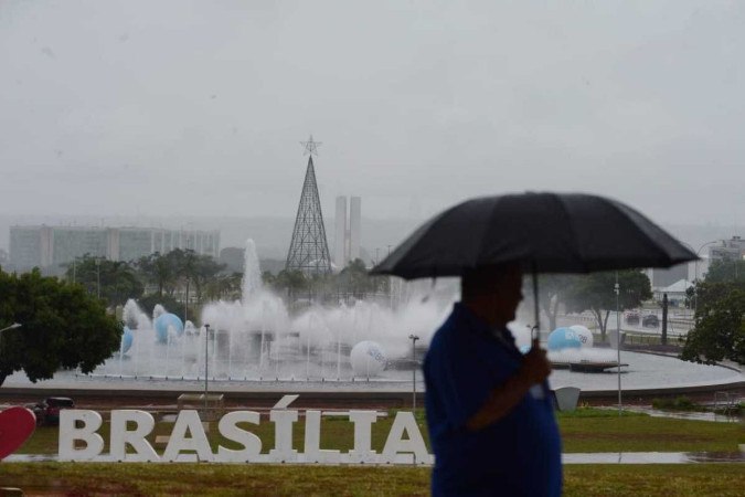 Homem se protege da chuva embaixo da Torre de TV, no centro de Brasília -  (crédito: Minervino Júnior/CB/D.A.Press)