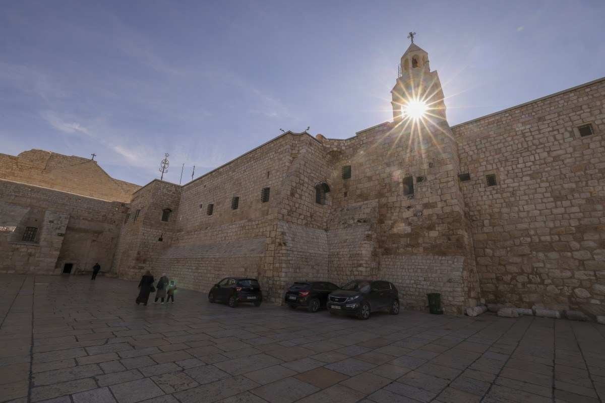Palestinos caminham pela praça vizinha do lado de fora da igreja onde encontra a gruta 