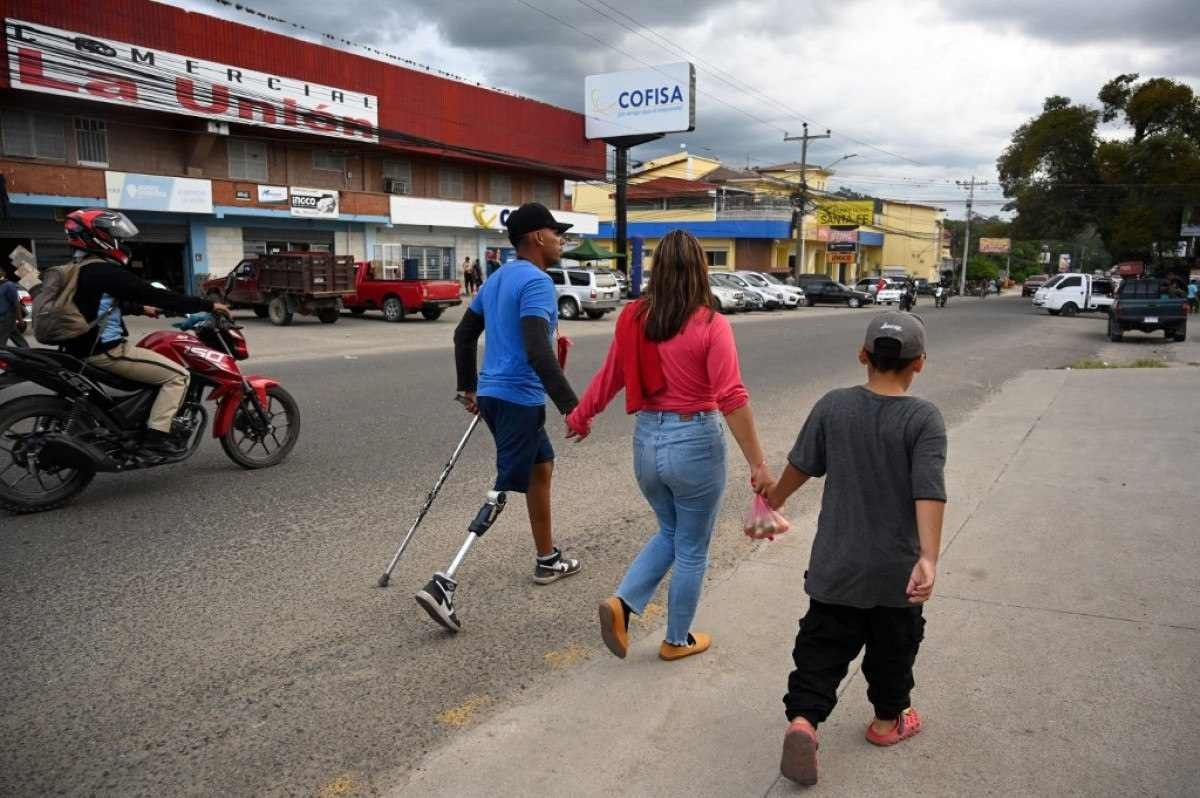 O migrante venezuelano Marcel Maldonado (L) caminha com sua esposa Andrea Loreto (C) e seu filho Samuel Maldonado em sua viagem até a fronteira Honduras-Guatemala, na cidade de Danli, departamento de El Paraiso, Honduras, em 3 de outubro de 2023