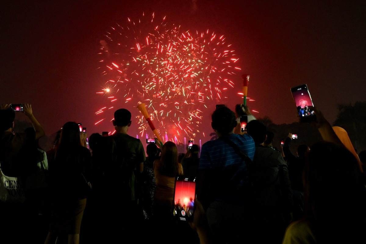 Os foliões assistem aos fogos de artifício iluminando o céu inaugurando o Ano Novo no Rizal Park, em Manila, em 1º de janeiro de 2024.      