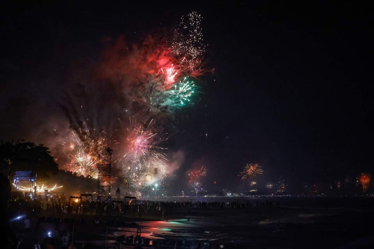 Fogos de artifício iluminam o céu noturno enquanto os foliões celebram o Ano Novo em uma praia no distrito de Kerobokan, na ilha turística de Bali, na Indonésia, em 1º de janeiro de 2024