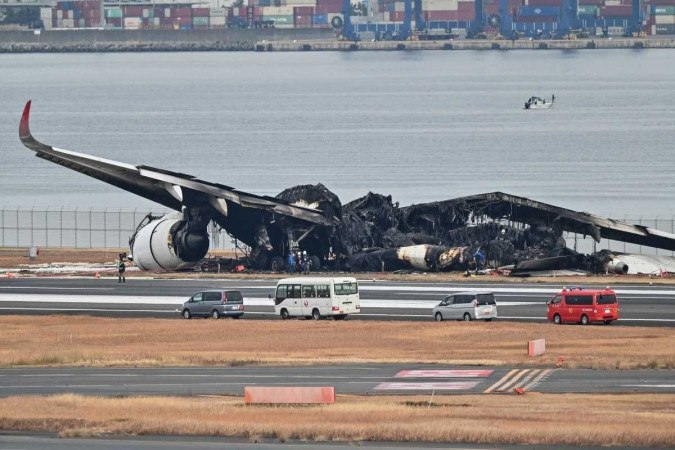 Destroços queimados de um avião de passageiros da Japan Airlines (JAL) na pista do Aeroporto Internacional de Tóquio, em Haneda -  (crédito: Richard A. Brooks / AFP)