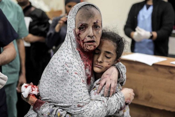 Palestina ferida, coberta de sangue e poeira, abraça criança, também em Khan Yunis  -  (crédito: Belal Khaled/AFP)