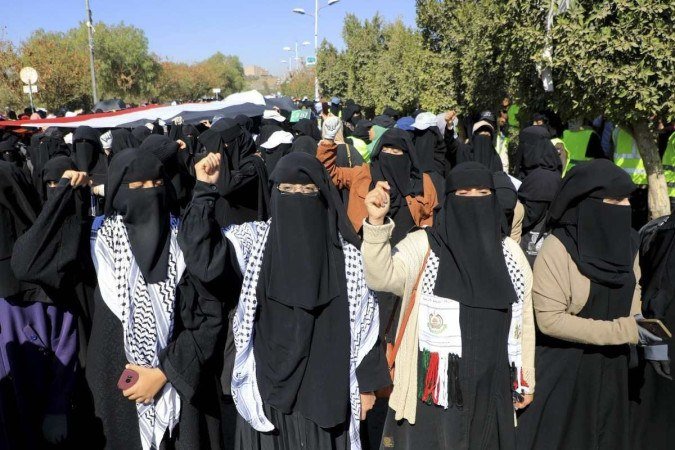 Mulheres iemenitas vestindo o keffiyeh, traje tradicional palestino, protestam contra Israel e EUA em Sanaa