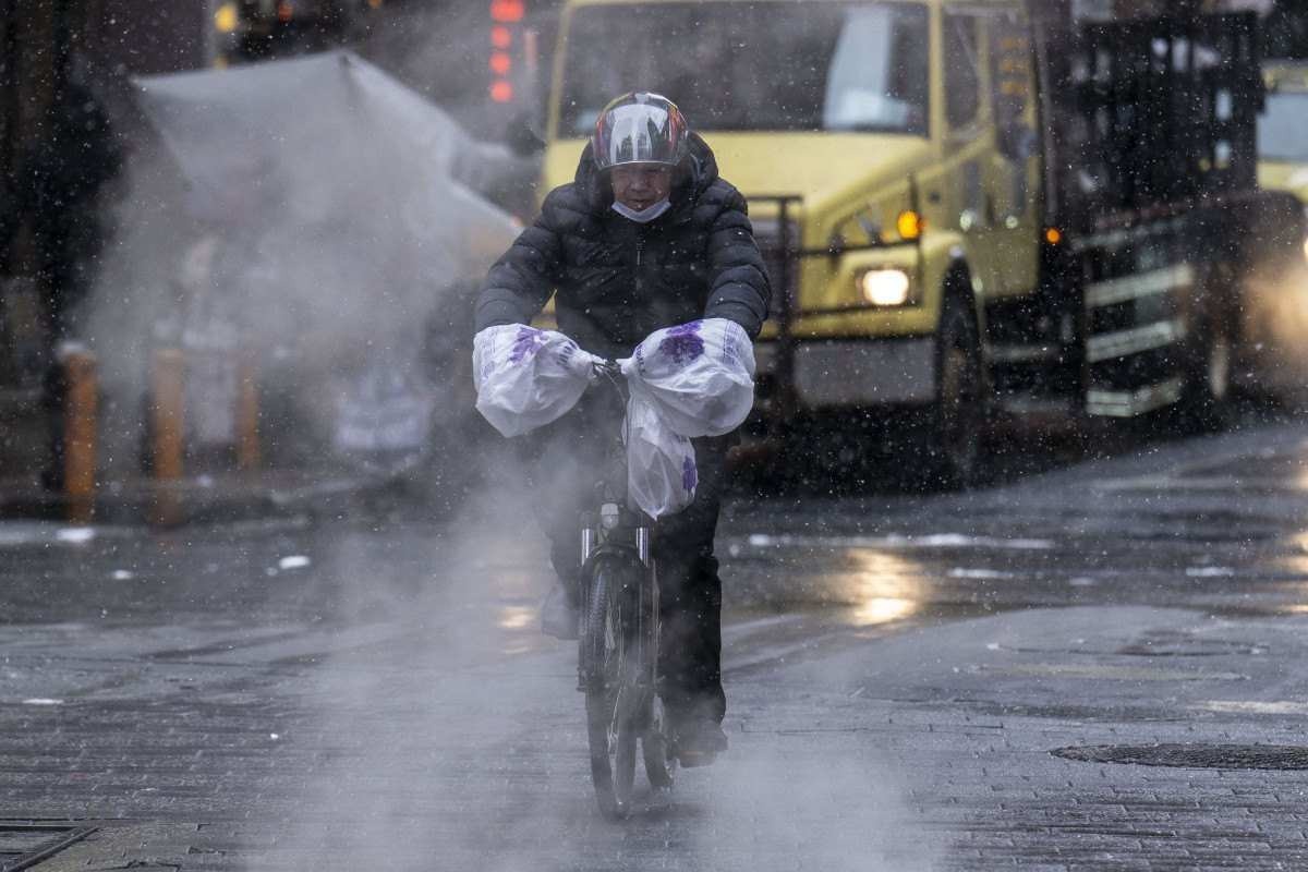 Uma pessoa em uma bicicleta de entrega atravessa a Times Square enquanto a neve cai durante uma tempestade de inverno em Nova York em 19 de janeiro de 2024