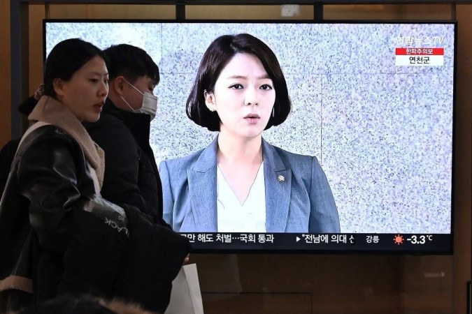 Pessoas passam por uma tela de televisão que mostra noticiário com filmagem do legislador do Partido do Poder Popular da Coreia do Sul, Bae Hyun-jin -  (crédito: JUNG YEON-JE / AFP)