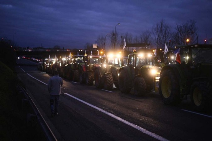  A French farmer walks past tractors after farmers moved their road block closer to Rungis wholesale food market, during a protest on the A6 highway near Longjumeau, south of Paris, on January 29, 2024, amid nationwide protests called by several farmers unions on pay, tax and regulations. Local branches of major farmer unions FNSEA and Jeunes Agriculteurs announced on January 27, 2024, a 