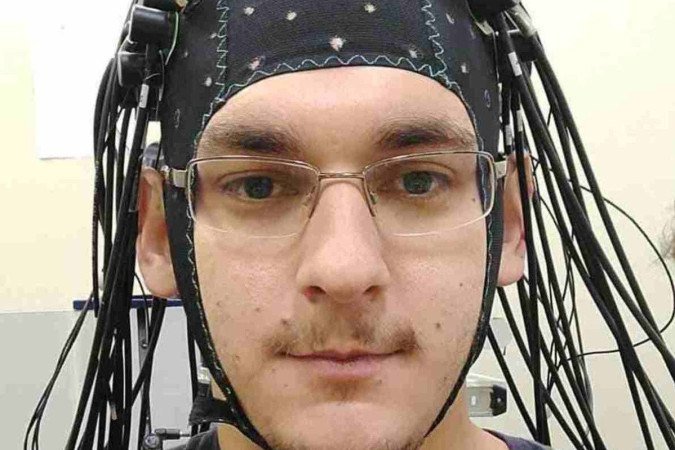 Capacete desenvolvido por Sérgio Luiz Novi Junior, ganhador do Prêmio Capes de Ciências Exatas, desempenha funções parecida a um ressonância magnética Homem branco de óculos usa touca preta de onde saem fios