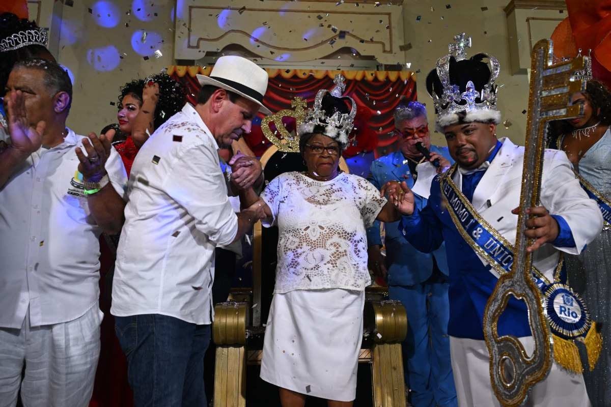 O prefeito do Rio de Janeiro, Eduardo Paes (L), o rei Momo Caio Cesar Dutra (R) e a cantora Tia Surica (C) gesticulam durante a cerimônia oficial de abertura do Carnaval no Rio de Janeiro      
