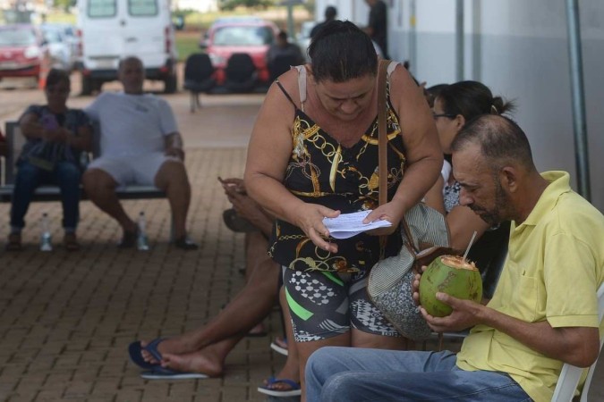 Com febre, Antônio Rodrigues se hidrata com água de côco, enquanto espera na fila  -  (crédito:  Ed Alves/CB/DA.Press)