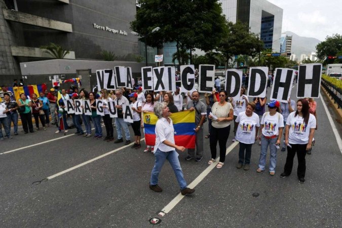 Manifestantes da oposição seguram cartazes que formam a frase 