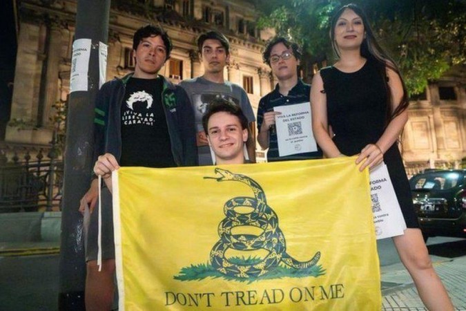 Membros do grupo Pibes Libertarios mostram uma bandeira de Gadsden, símbolo do libertarianismo -  (crédito: BBC)