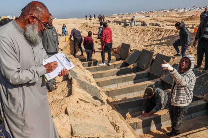 Homem anota os nomes de palestinos mortos em ataques, num cemitério improvisado em Rafah, no sul da Faixa de Gaza -  (crédito:  AFP)
