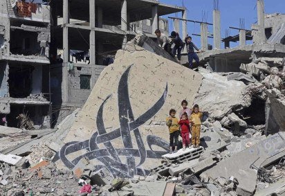 Crianças posam ao lado de um mural que restou em escombros de um edifício destruído em Rafah -  (crédito:  MOHAMMED ABED / AFP) -Crianças posam ao lado de um mural que restou em escombros de um edifício destruído em Rafah -  (crédito:  MOHAMMED ABED / AFP)