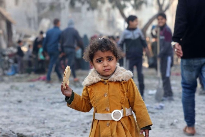 Menina palestina tenta se alimentar durante bombardeio em Rafah -  (crédito: AFP)