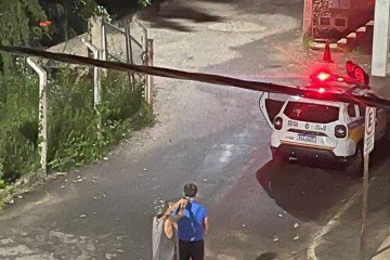 Imagem de câmera de segurança mostra o rapaz fazendo o prefeito refém em frente ao quartel, onde um policial atrás de uma viatura negocia a sua rendição -  (crédito: Divulgação/PMMG)