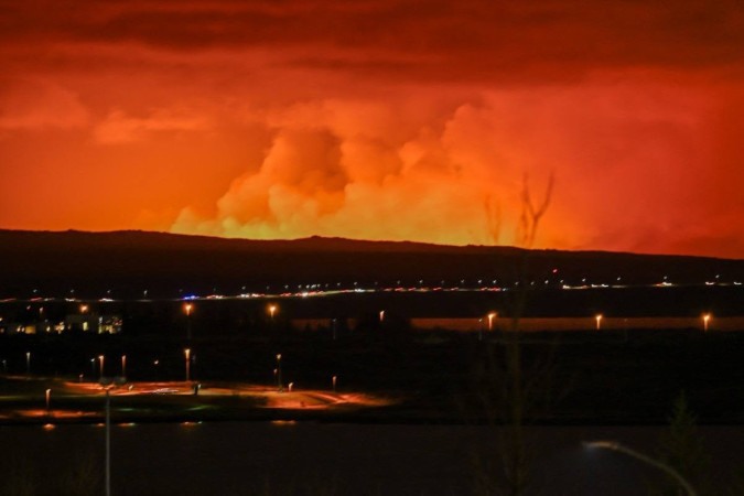 
O céu está colorido de laranja enquanto a lava derretida flui de uma fissura na península de Reykjanes, ao norte da cidade evacuada de Grindavik, oeste da Islândia -  (crédito: HALLDOR KOLBEINS / AFP)