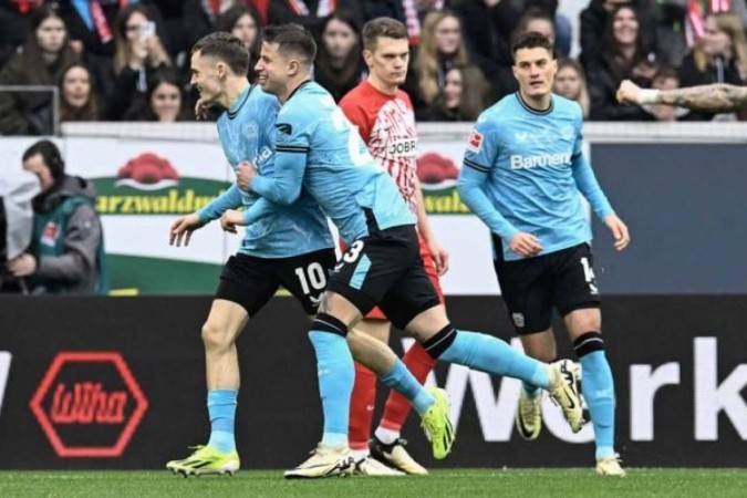 Florian Wirtz (de azul) tenta dominar a bola para o Leverkusen, mas recebe a marcação de Sildillia  -  (crédito:  AFP /AFP via Getty Images)