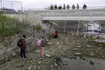 Em Eagle Pass, no Texas, soldados e policiais observam imigrantes que cruzaram o Rio Grande para tentar entrar nos EUA -  (crédito:  Getty Images via AFP)