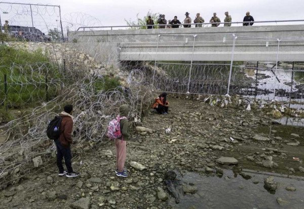 Em Eagle Pass, no Texas, soldados e policiais observam imigrantes que cruzaram o Rio Grande para tentar entrar nos EUA -  (crédito:  Getty Images via AFP)