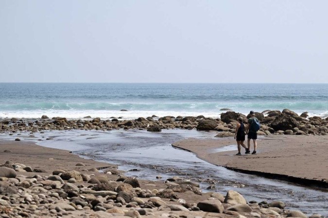 Turistas caminham na praia de El Zonte, El Salvador, um dos locais onde o uso do bitcoin tem sido mais promovido, no dia 16 de março       -  (crédito: Marvin RECINOS / AFP)