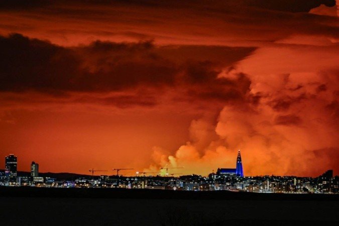  (FILES) The skyline of Reykjavik is against the backdrop of orange coloured sky due to molten lava flowing out from a fissure on the Reykjanes peninsula north of the evacuated town of Grindavik, western Iceland on March 16, 2024. Global temperatures 