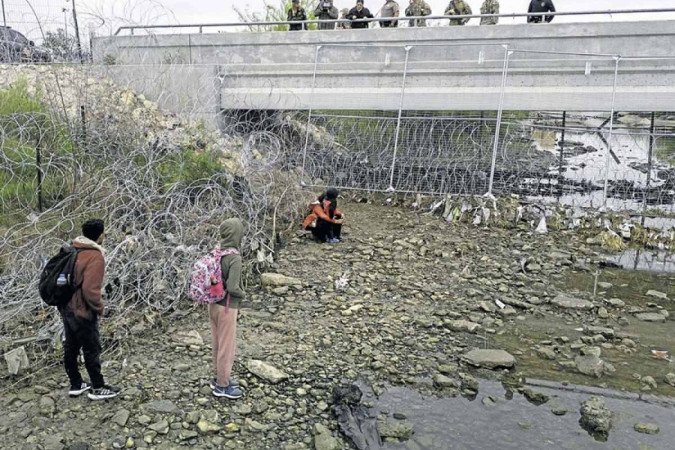 Em Eagle Pass, no Texas, soldados e policiais observam imigrantes que cruzaram o Rio Grande para tentar entrar no território americano -  (crédito:  Getty Images via AFP)