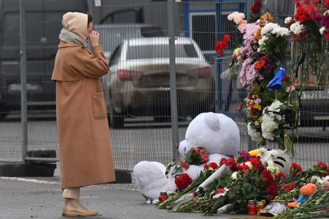 Mulher chora em memorial que começa a se formar em frente ao Crocus City Hall, local do atentado -  (crédito: AFP)