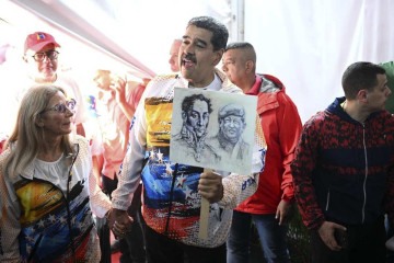Acompanhado da primeira-dama Cilia Flores, Maduro exibe imagens de Simón Bolívar e de Hugo Chávez, ao visitar o Conselho Nacional Eleitoral  -  (crédito: Federico Parra/AFP)