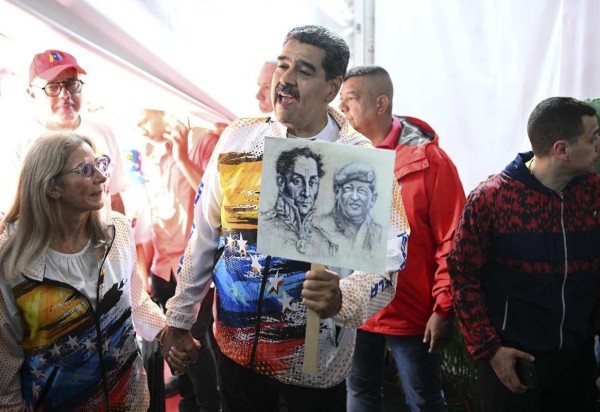 Acompanhado da primeira-dama Cilia Flores, Nicolás Maduro exibe imagens de Simón Bolívar e de Hugo Chávez, ao visitar o Conselho Nacional Eleitoral  -  (crédito: Federico Parra/AFP)