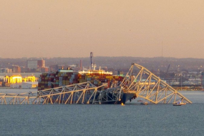       A estrutura de aço da ponte Francis Scott Key fica no topo de um navio porta-contêineres depois que ele atingiu a ponte em Baltimore, Maryland, em 26 de março de 2024. O colapso fez com que vários veículos e até 20 pessoas mergulhassem no porto abaixo. -  (crédito: ROBERTO SCHMIDT / AFP)