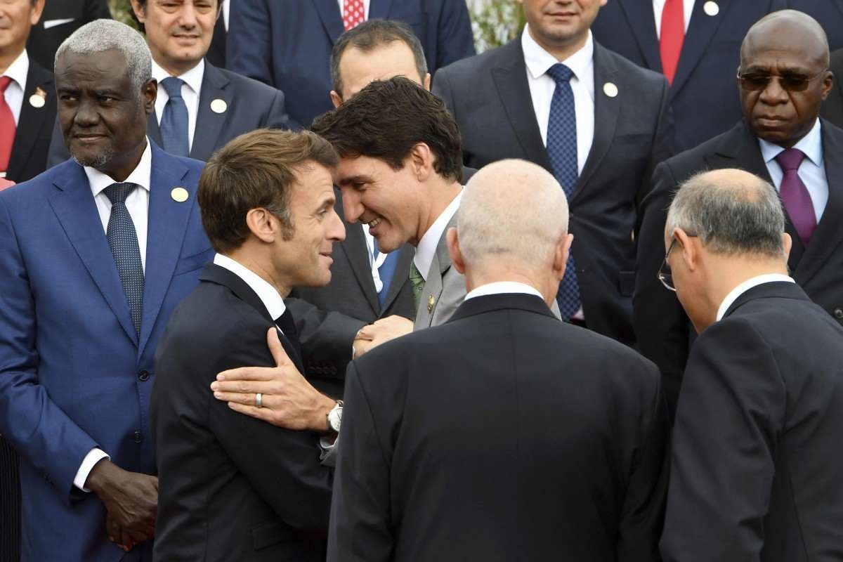O presidente da França, Emmanuel Macron, e o primeiro-ministro do Canadá, Justin Trudeau, cumprimentam-se enquanto os chefes dos países francófonos posam para uma foto de grupo durante a abertura da 18ª Cúpula da Francofonia na ilha turística tunisina de Djerba, em 19 de novembro de 2022