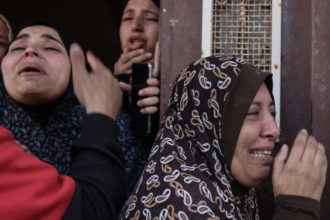 Mulheres palestinas choram enquanto os corpos de familiares são retirados de prédio, em Rafah