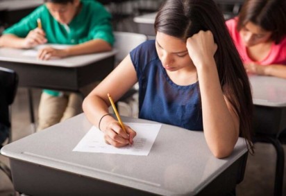 Mulher sentada em uma sala de aula fazendo uma prova -  (crédito: Reprodução/Freepik)