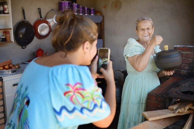 Dona Maria com as netas Laila e Michele, que a ajudam com os vídeos e a administração das redes. Abaixo, Laila filmando a avó: rotina diária
