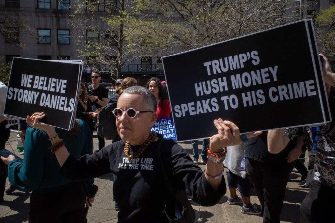  NEW YORK, NEW YORK - APRIL 15: An anti-Trump activist confronts Trump supporters with signs at Collect Pond Park on the first day of his hush money trial on April 15, 2024 in New York City. Jury selection is set to begin in the former president's criminal trial. Trump faces 34 felony counts of falsifying business records in the first of his criminal cases to go to trial. This is the first-ever criminal trial of a former president of the United States.   David Dee Delgado/Getty Images/AFP (Photo by David Dee Delgado / GETTY IMAGES NORTH AMERICA / Getty Images via AFP)
      