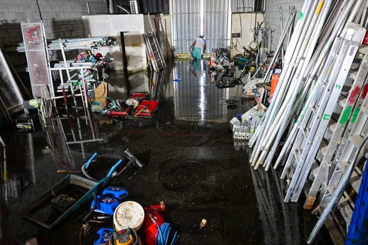  A man wades through a flooded warehouse in Dubai following heavy rains on April 18, 2024. Dubais giant highways were clogged by flooding and its major airport was in chaos as the Middle East financial centre remained gridlocked on April 18, a day after the heaviest rains on record. (Photo by Giuseppe CACACE / AFP)       