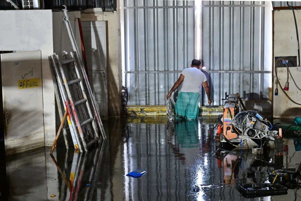  A man wades through a flooded warehouse in Dubai following heavy rains on April 18, 2024. Dubais giant highways were clogged by flooding and its major airport was in chaos as the Middle East financial centre remained gridlocked on April 18, a day after the heaviest rains on record. (Photo by Giuseppe CACACE / AFP)       