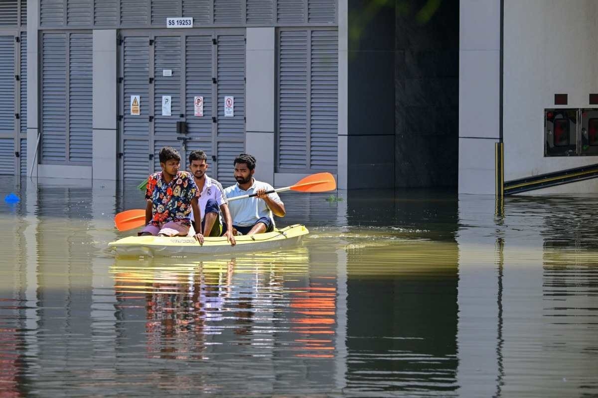  People ride in a canoe on a flooded street in Dubai following heavy rains on April 18, 2024. Dubais giant highways were clogged by flooding and its major airport was in chaos as the Middle East financial centre remained gridlocked on April 18, a day after the heaviest rains on record. (Photo by Giuseppe CACACE / AFP)       