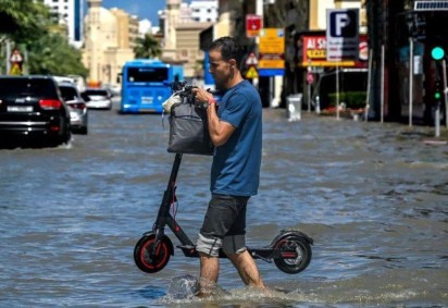 Pessoas caminham pelas ruas alagadas em decorrência das enchentes causadas pelas fortes chuvas em Dubai -  (crédito: Reuters)