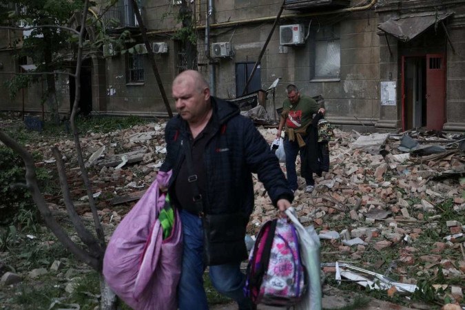 Moradores abandonam um prédio atingido por mísseis russos na cidade ucraniana de Dnipro -  (crédito:  AFP)