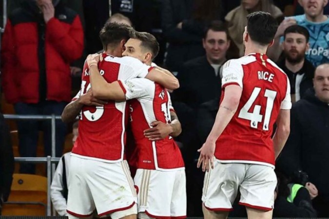  Arsenal's Belgian midfielder #19 Leandro Trossard (C) celebrates with teammates after scoring the opening goal of the English Premier League football match between Wolverhampton Wanderers and Arsenal at the Molineux stadium in Wolverhampton, central England on April 20, 2024. (Photo by HENRY NICHOLLS / AFP) / RESTRICTED TO EDITORIAL USE. No use with unauthorized audio, video, data, fixture lists, club/league logos or 'live' services. Online in-match use limited to 120 images. An additional 40 images may be used in extra time. No video emulation. Social media in-match use limited to 120 images. An additional 40 images may be used in extra time. No use in betting publications, games or single club/league/player publications. /  (Photo by HENRY NICHOLLS/AFP via Getty Images)
     -  (crédito:  AFP via Getty Images)